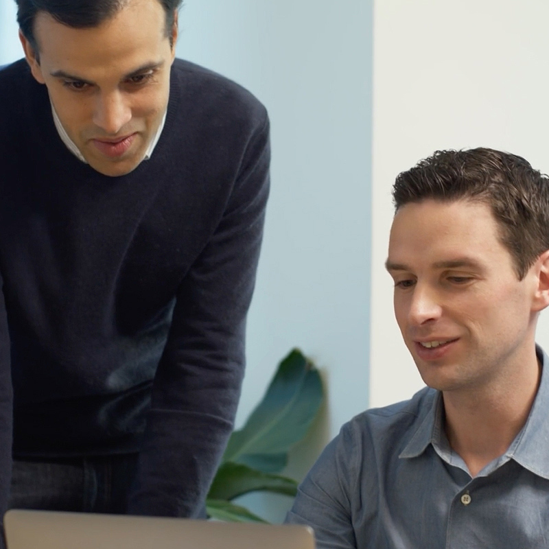 2 men looking at laptop screen.