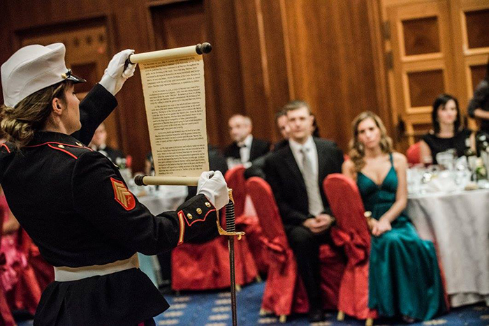 Sgt. Lyday stands with an open scroll to read a message for the 240th U.S. Marine Corps Ball in Prague.