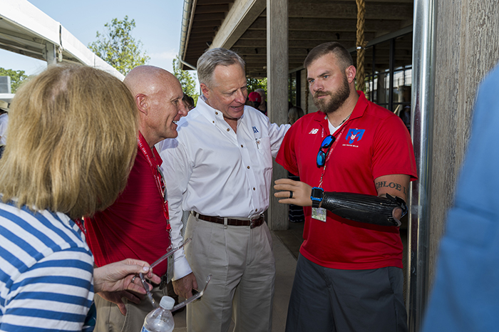 Ross Perot Jr. and other Memorial Day picnic attendees chat with retired Army Staff Sgt. Travis Mills.