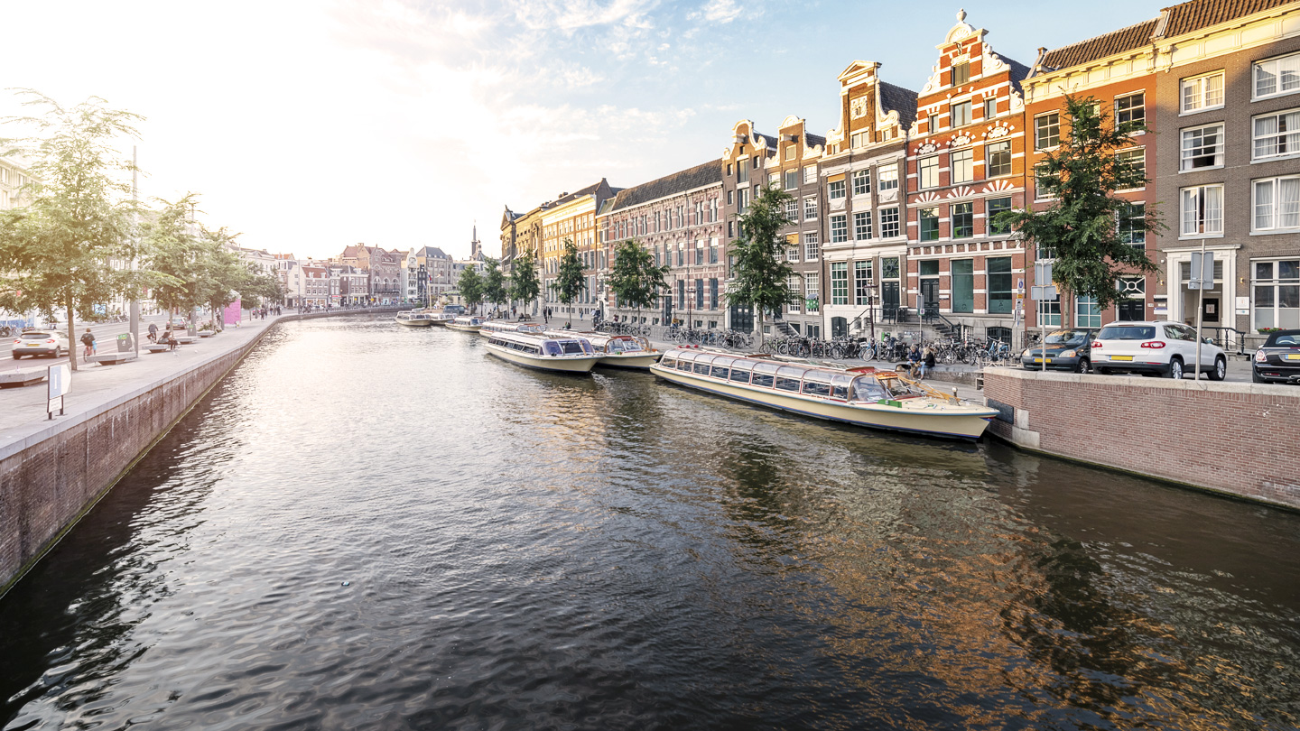 photo of a river with boats and buildings on the side. 