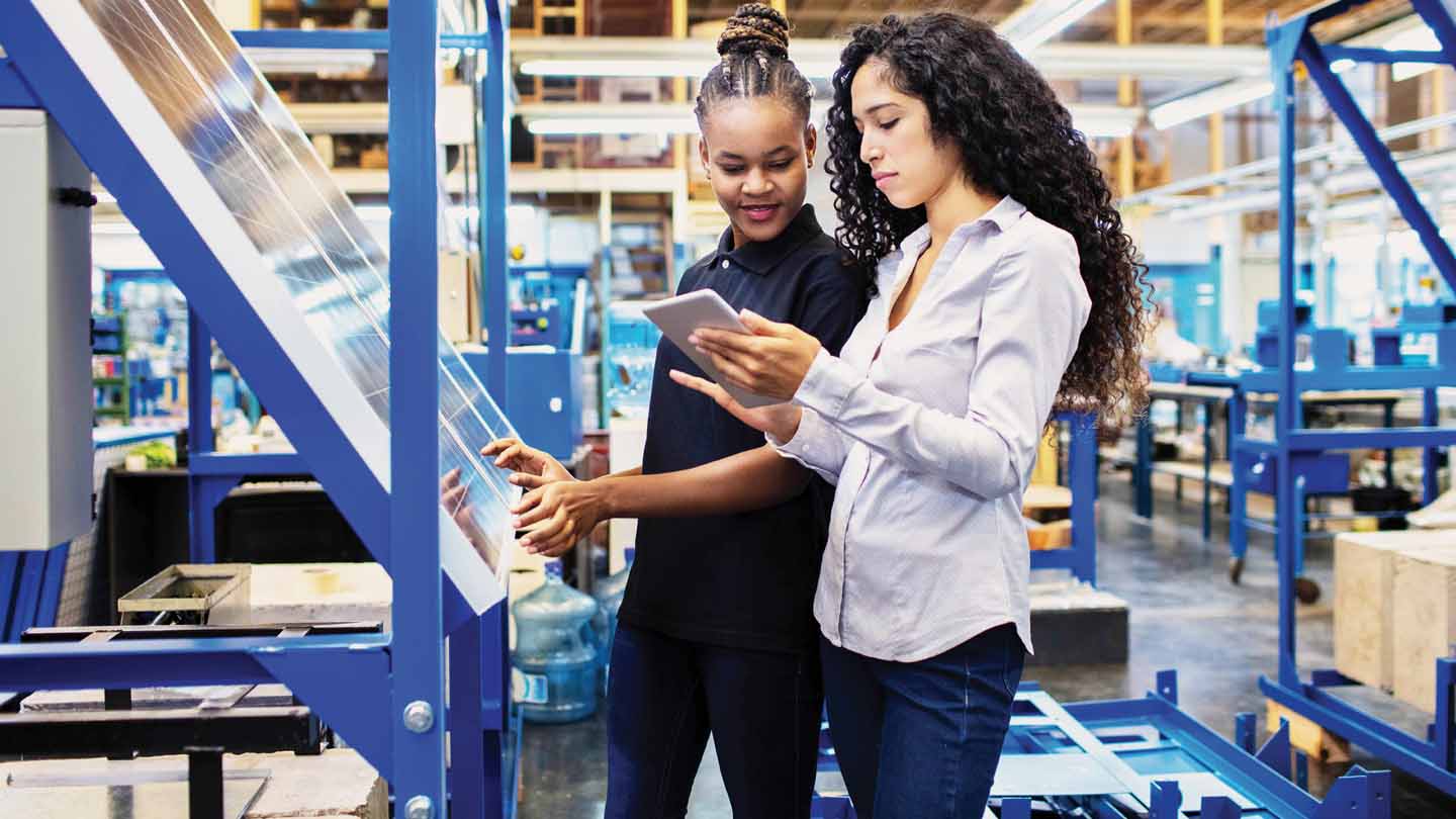 Two people in a warehouse looking at boxes of product and a tablet