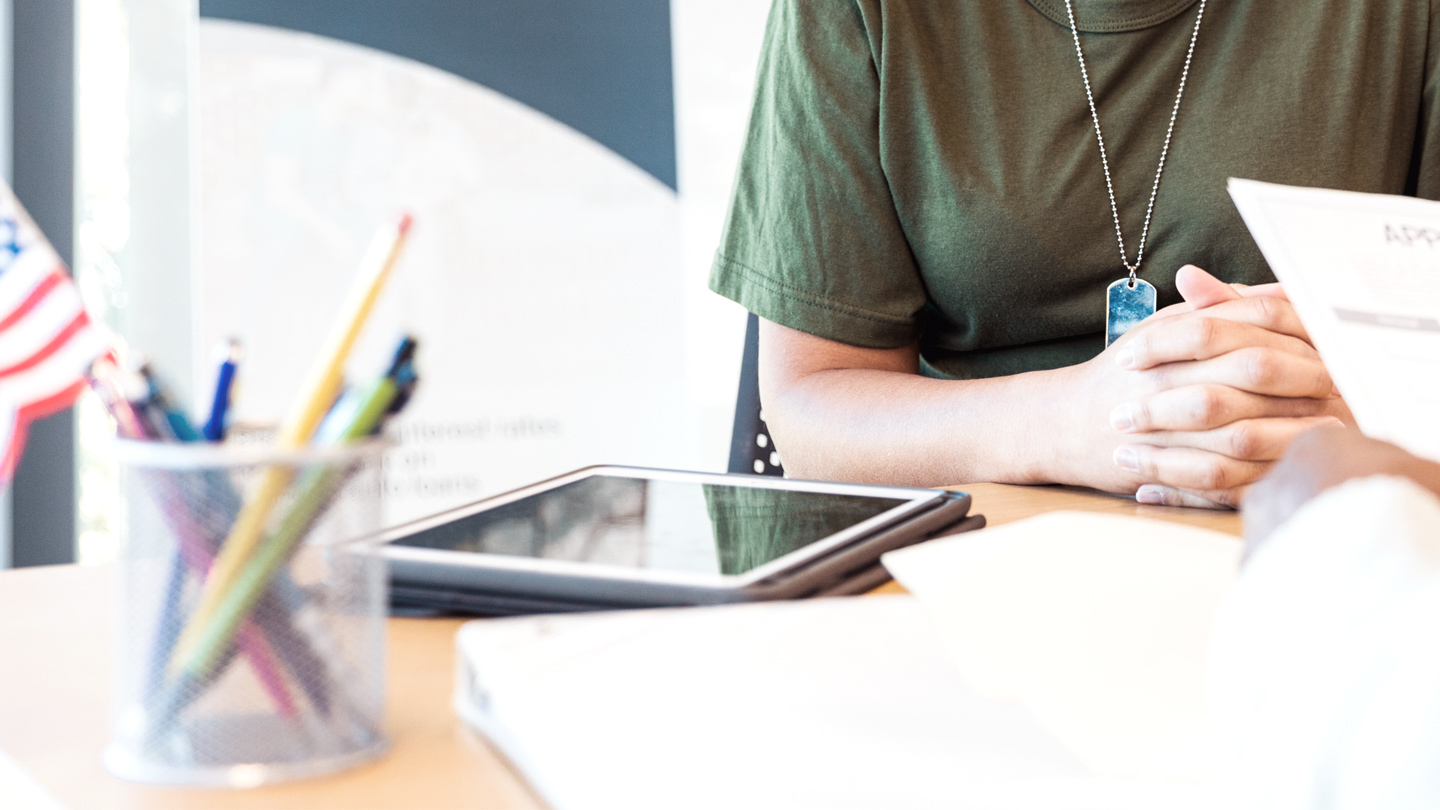 Photo of veteran sitting at a business desk talking to another person