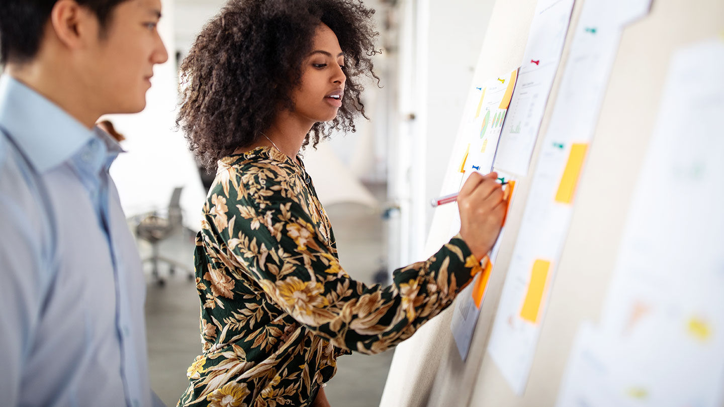 Woman and man talking in a business meeting and taking notes on a white board