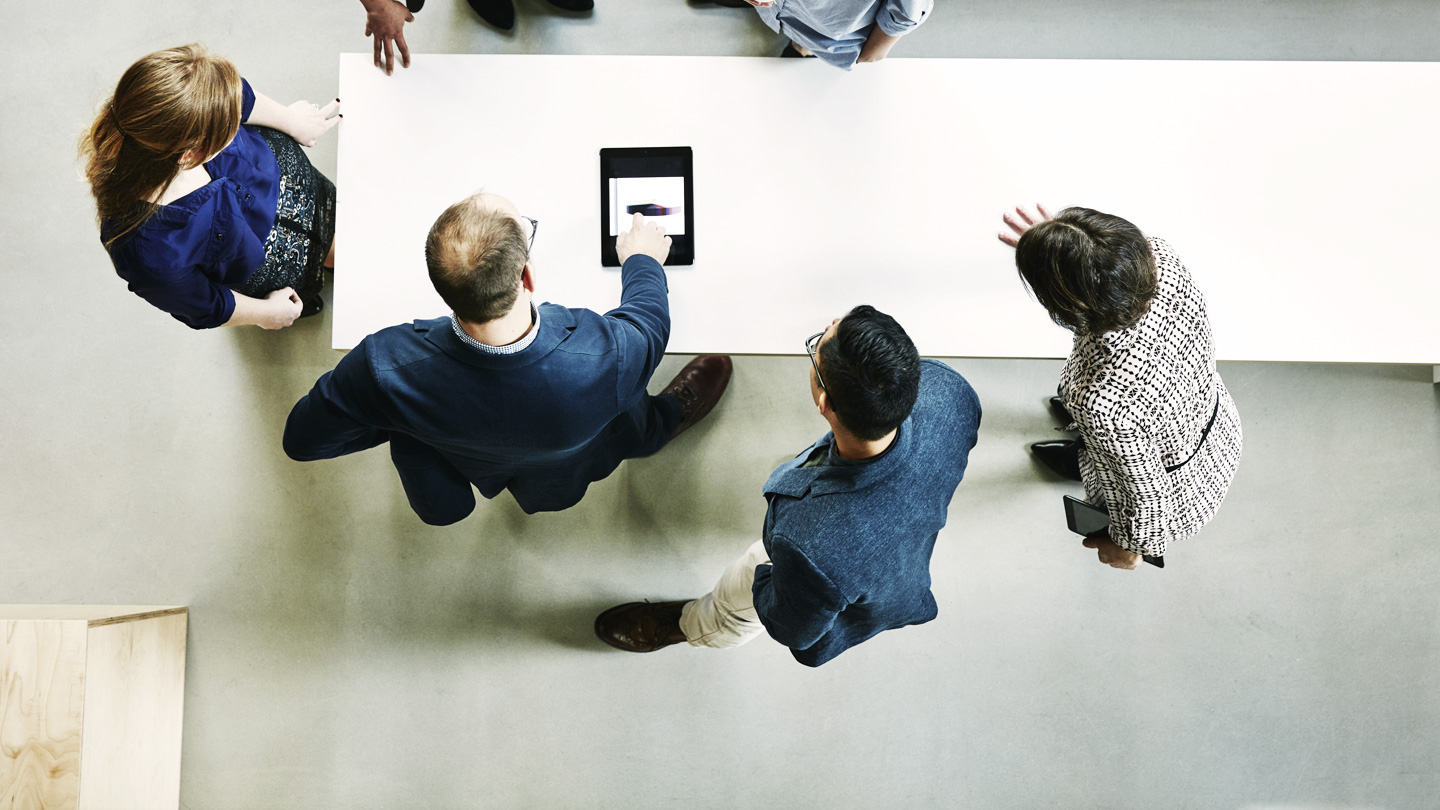 Workers around table looking at tablet