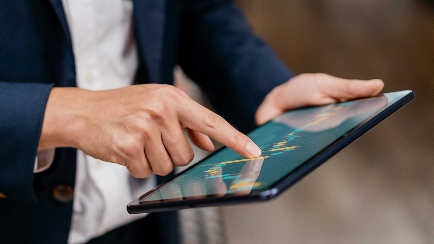 Image of an Asian businessman checking stock market chart on digital tablet. Fund manager looking at stock market chart on digital tablet.