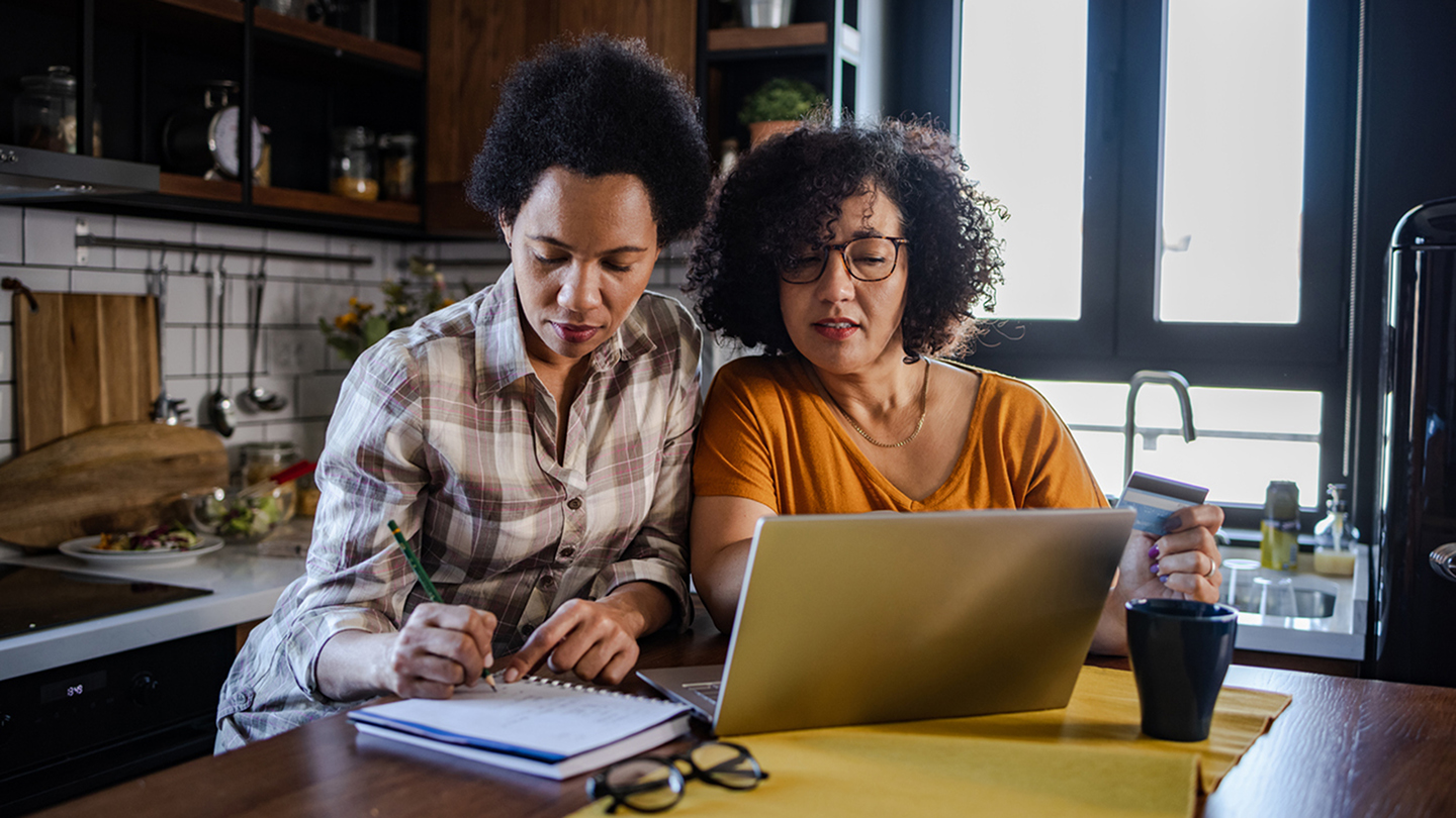 Two mature woman paying bills