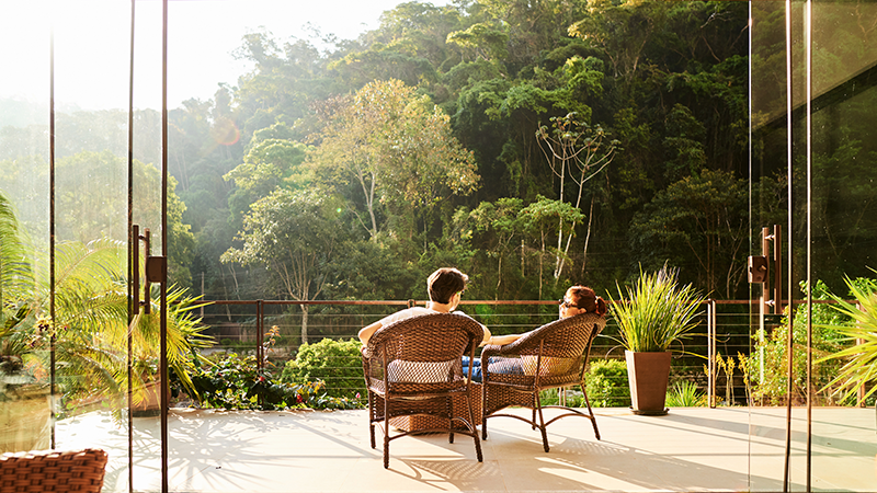 Rear view of a couple relaxing in the chairs at hotel balcony