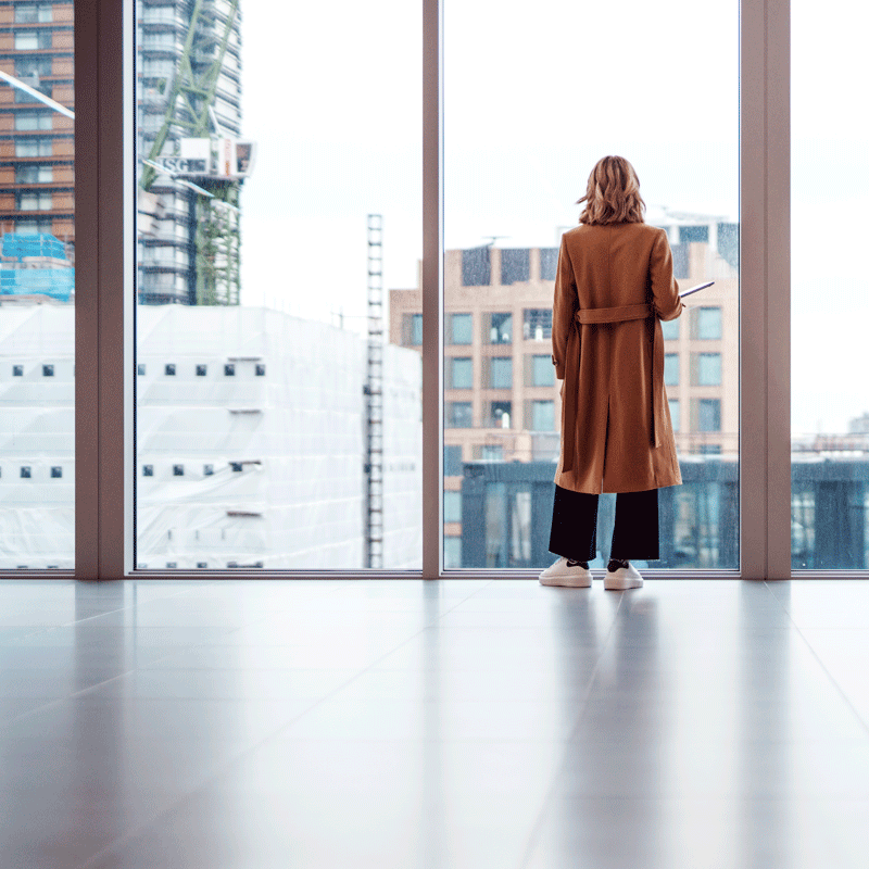 Woman standing looking outside of commercial building