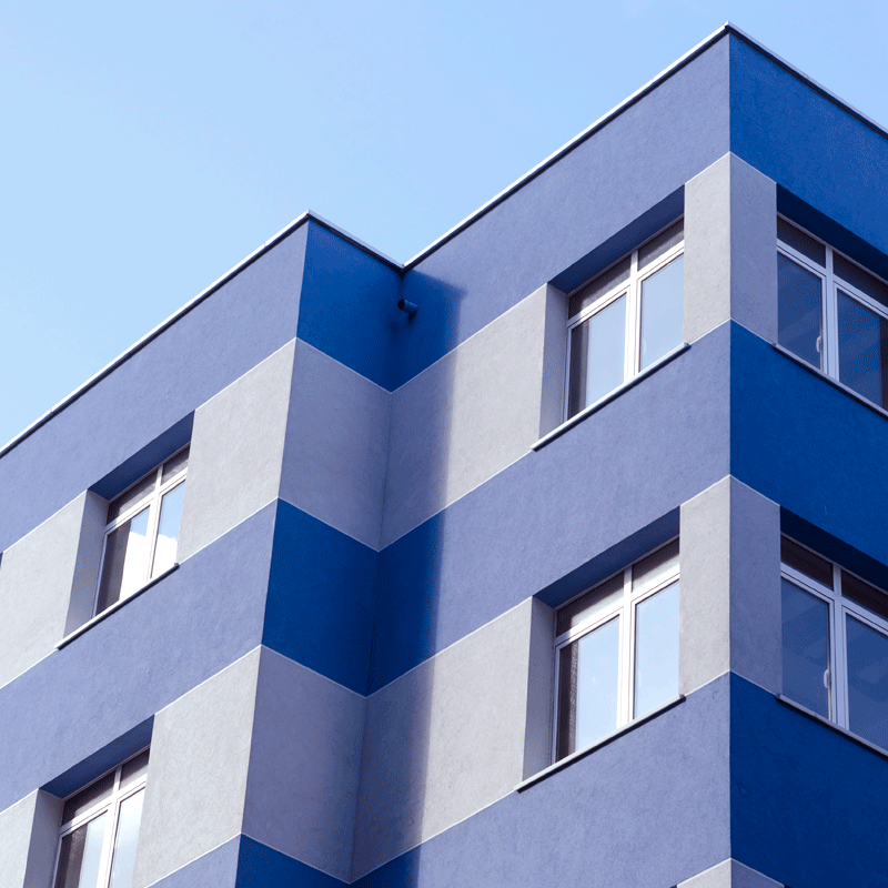 Corner of a blue building with sky in the background