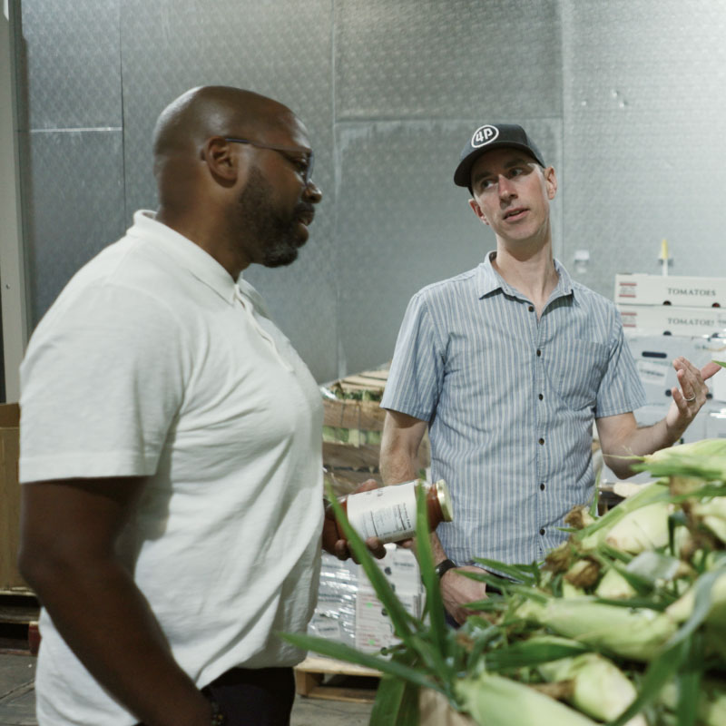 Two men talking near produce