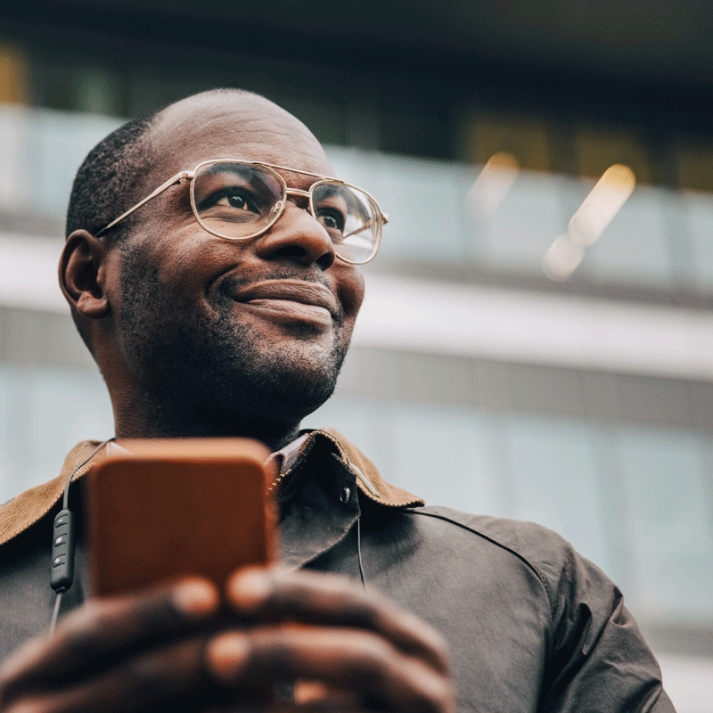 Man looking up from his cell phone smiling