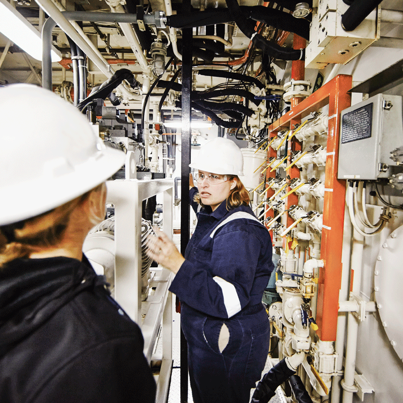 Two women wearing safety gear in equipment room