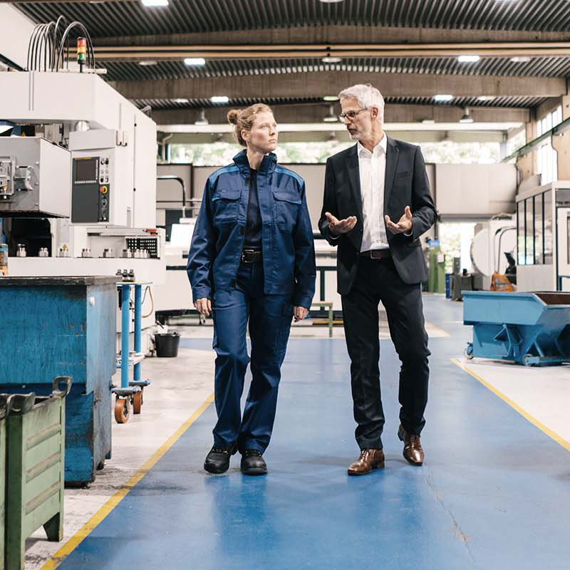 2 people walking inside a factory
