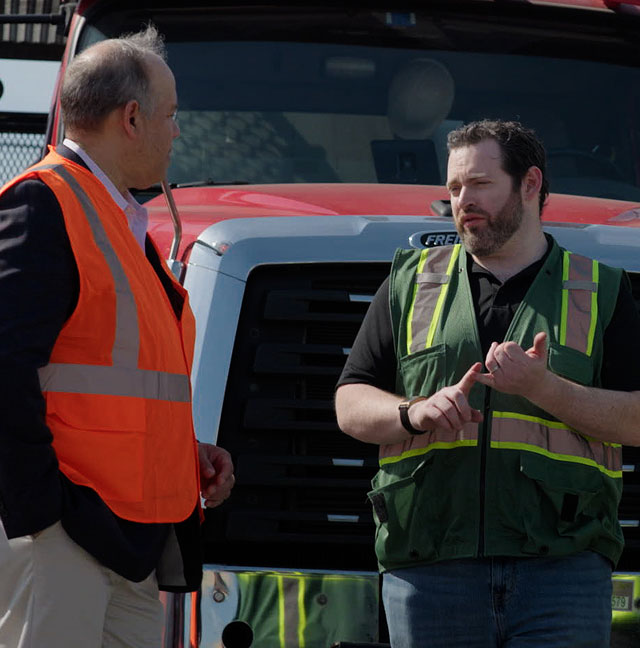 People discussing operations in front of a lumber delivery truck.