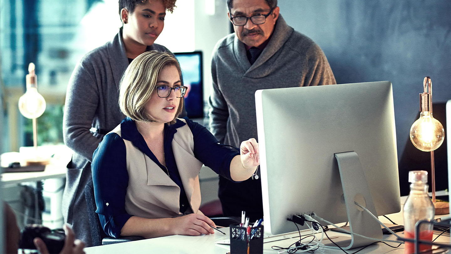 Three professionals looking at a computer