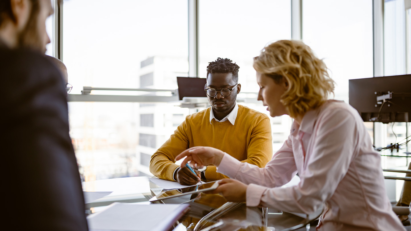 3 people in a meeting looking at a tablet