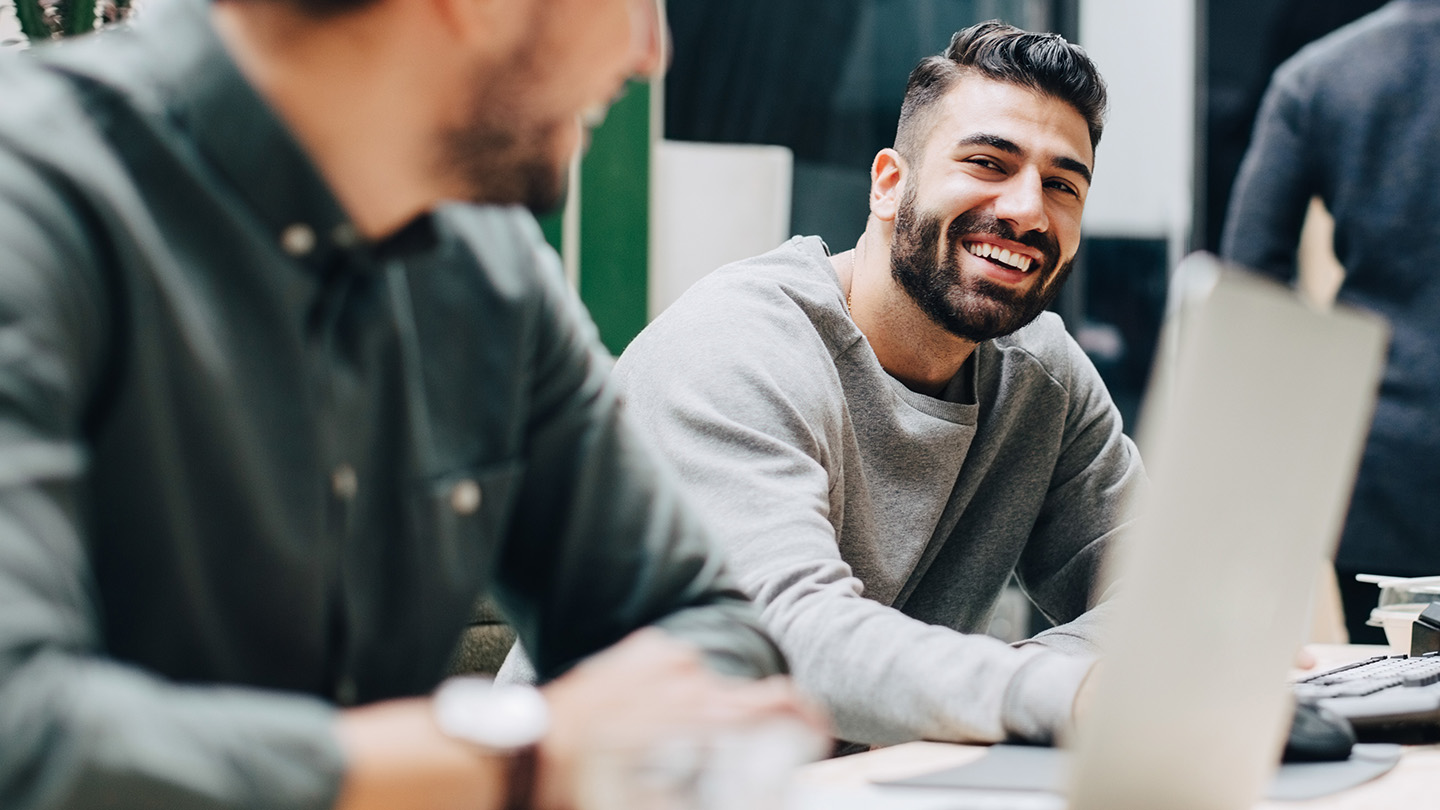 Person sitting at desk smiling on laptop