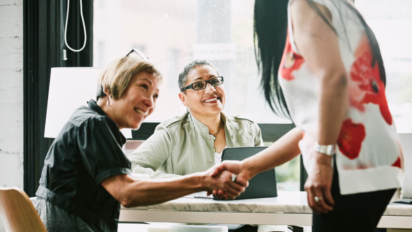 Group of people at a table talking and shaking hands