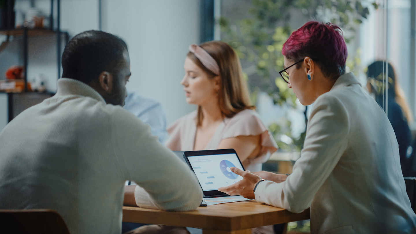 Two people sitting at table looking at presentation on laptop together