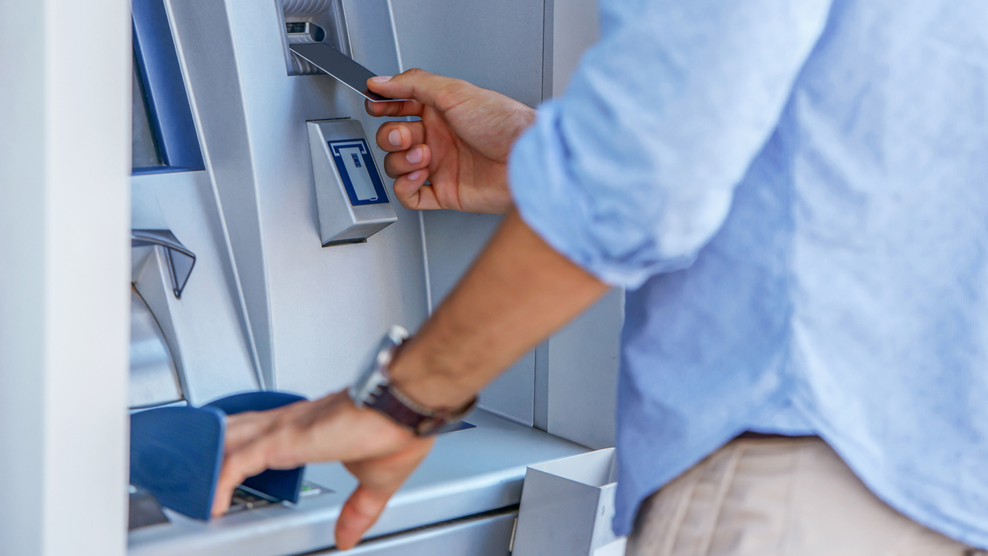 Man using a street ATM machine and withdrawing money, close up photo