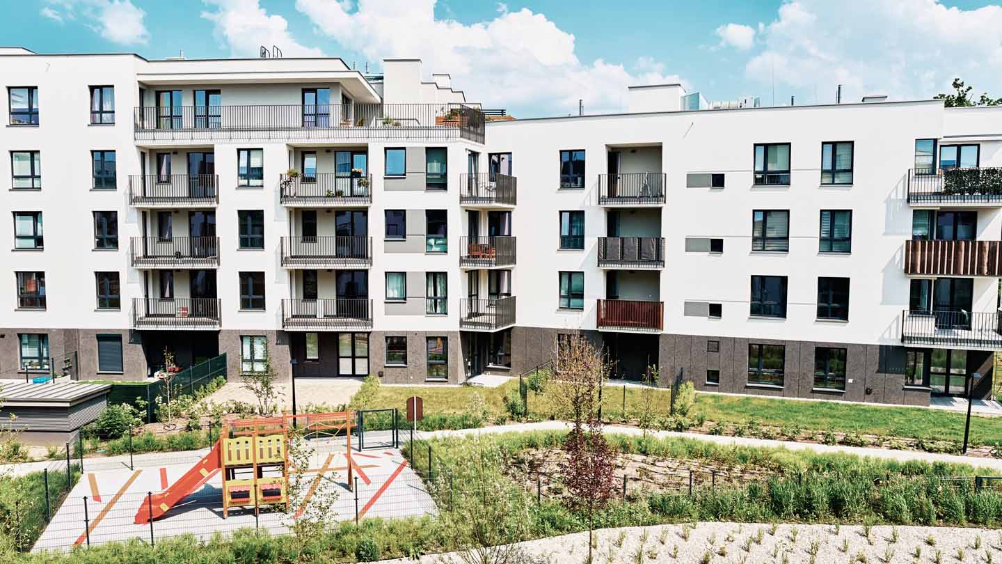 Contemporary apartment building with a playground area and green space in the foreground