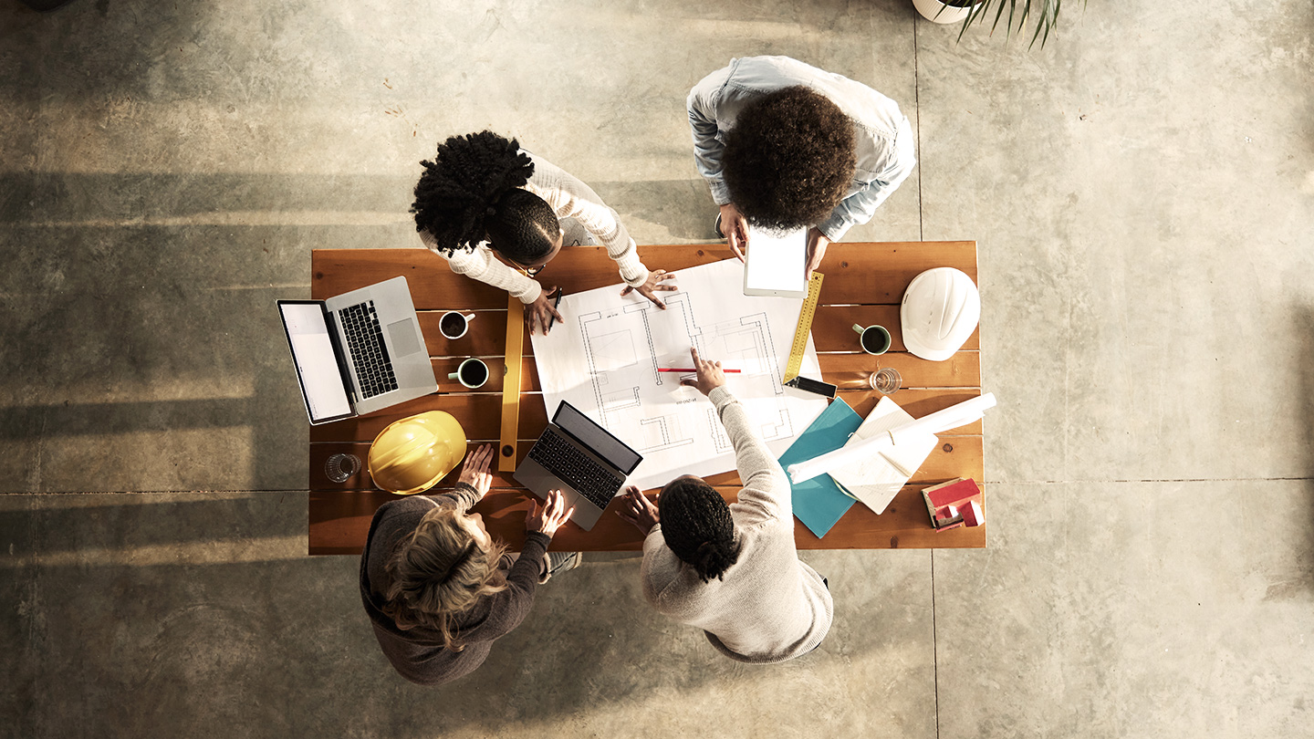 Aerial view of people leaning over a table looking at building plans