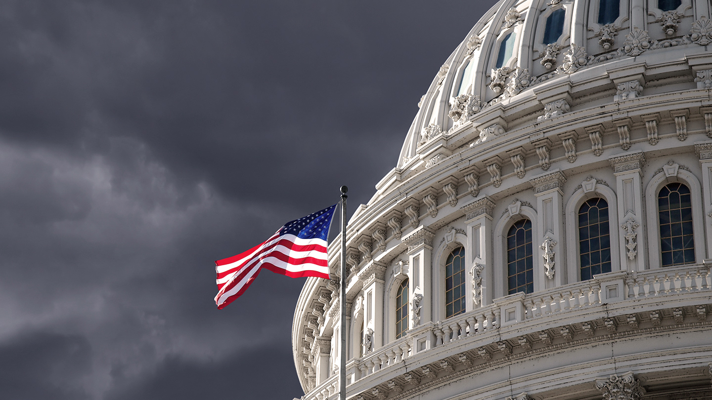 United States flag against a cloudy sky next to a building
