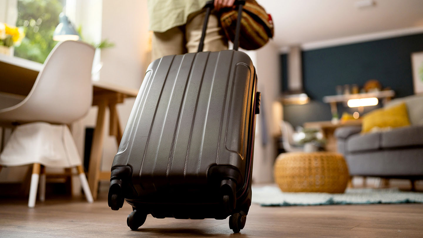 A person walks into a rental unit with a suitcase.