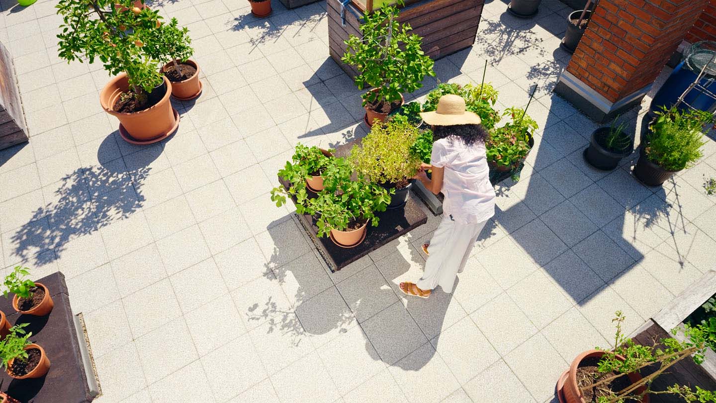 A woman tends to potted plants in an outdoor space near her apartment complex.