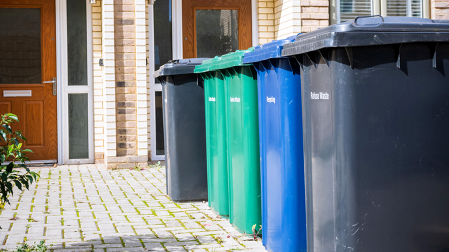 Refuse and recycling bins sit outside of a multifamily property