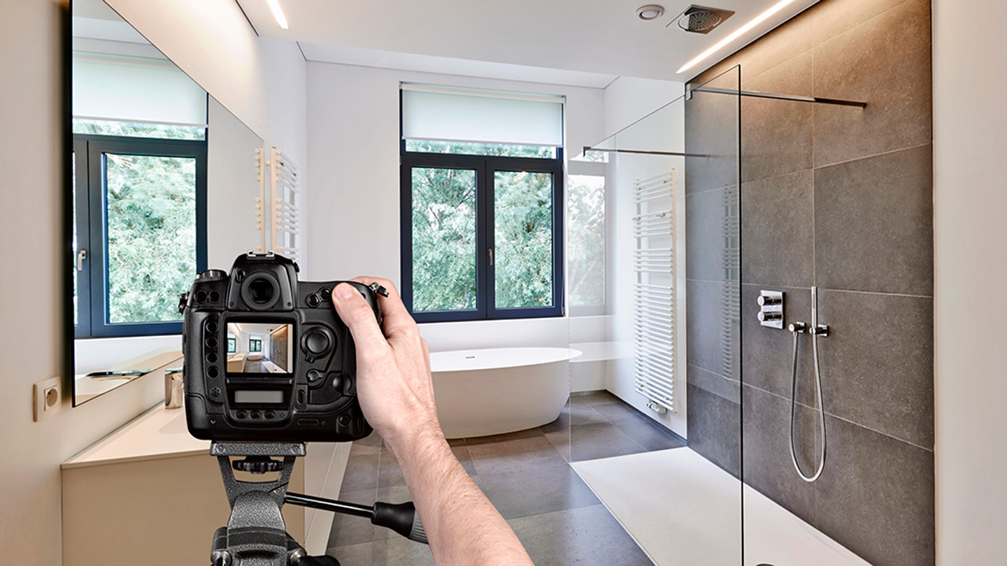 Man uses a professional camera to capture images of an apartment's bathroom