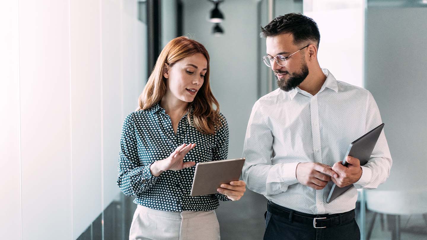 2 people talking to each other with tablets in their hands banner