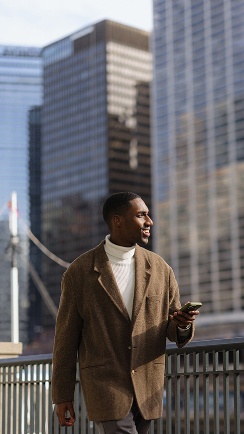 Person walking with phone by a bridge