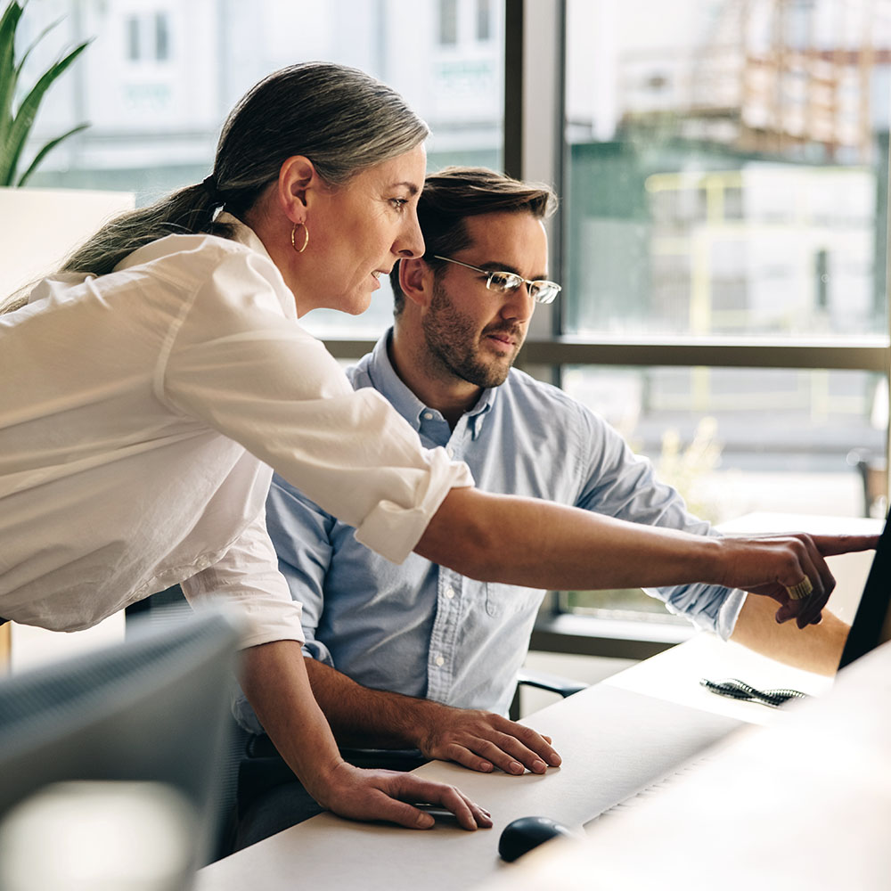 Two professionals consulting with one individual pointing at a monitor