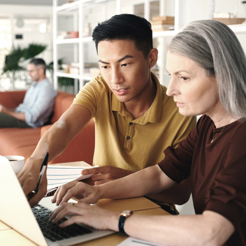 Individual pointing at a laptop while another person types