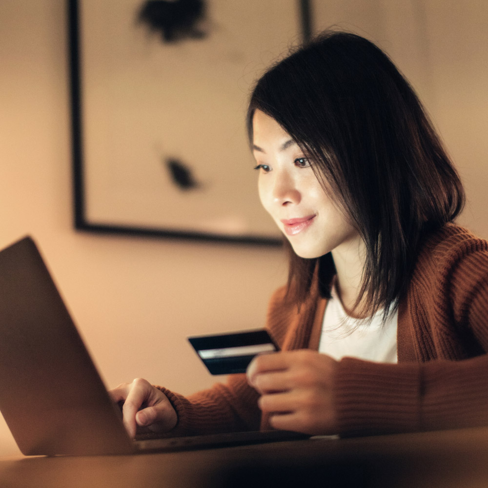 Consumer holding a credit card and looking at a laptop
