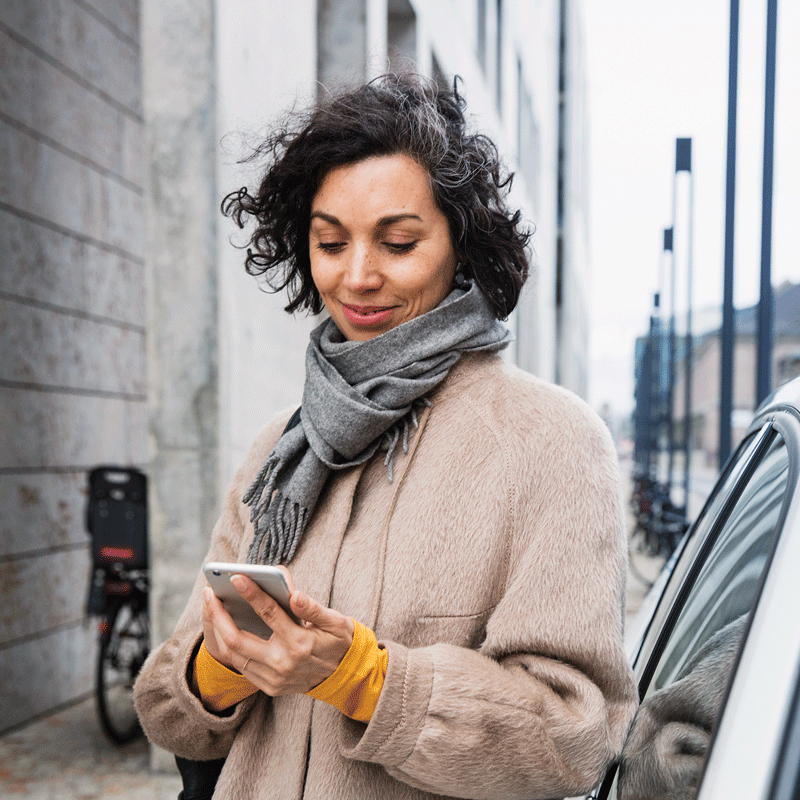 Women standing on street lookin down at phone