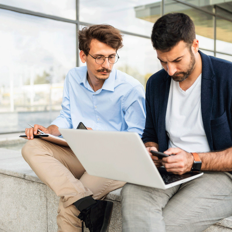 Two people working over laptop