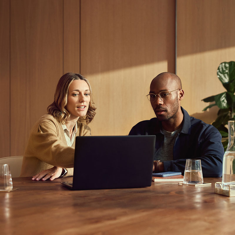 2 people using laptop in office