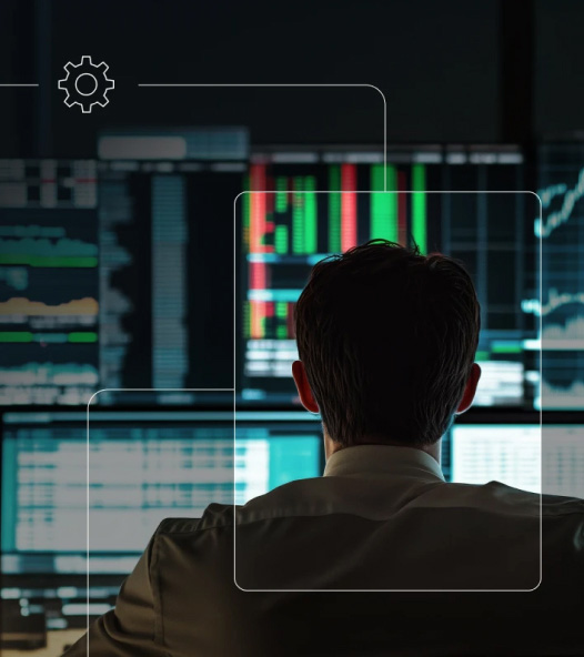 Rear view of a person in an office or trading environment facing multiple large monitors filled with charts and market-style data, with a small gear icon and thin interface overlay lines framing the scene.