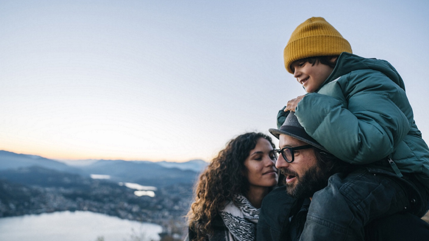 Portrait of family on mountain top above lake at sunset