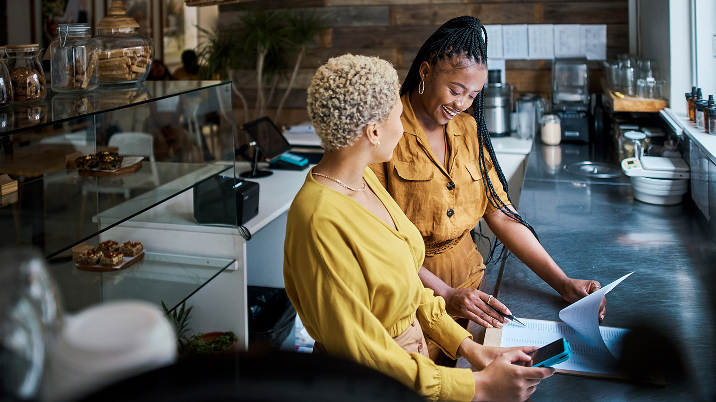 Small business owners talking and discussing the performance of their coffee shop. Black female entrepreneurs in a partnership collaborating and planning growth together inside their cafe or shop