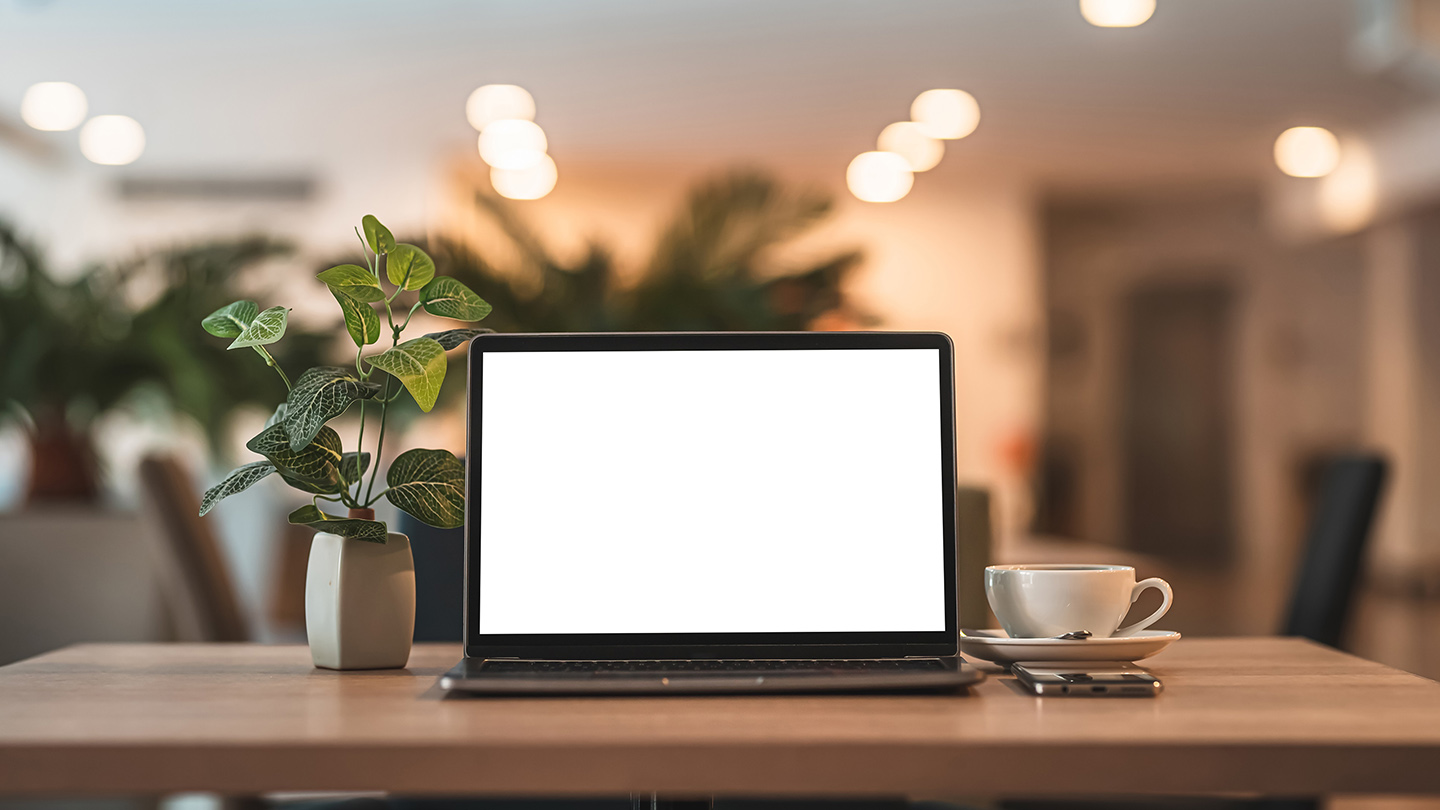 Mockup of laptop computer with empty screen with coffee cup and smartphone on table of the coffee shop background,White screen
