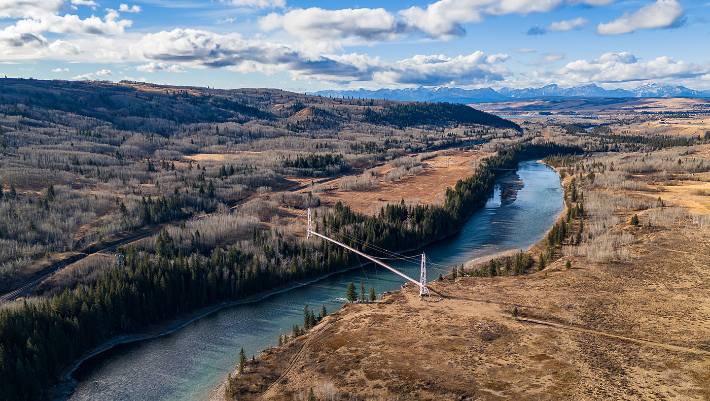 Gas pipeline bridge crossing over the Bow river with Canadian Rocky Mountains at background near Cochrane Alberta Canada