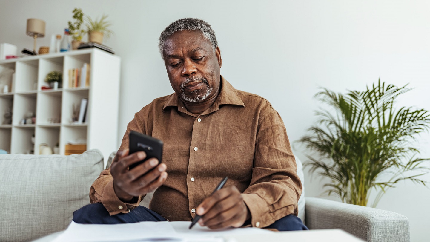 Depressed Senior Adult Man With Stacks of Papers and Envelopes