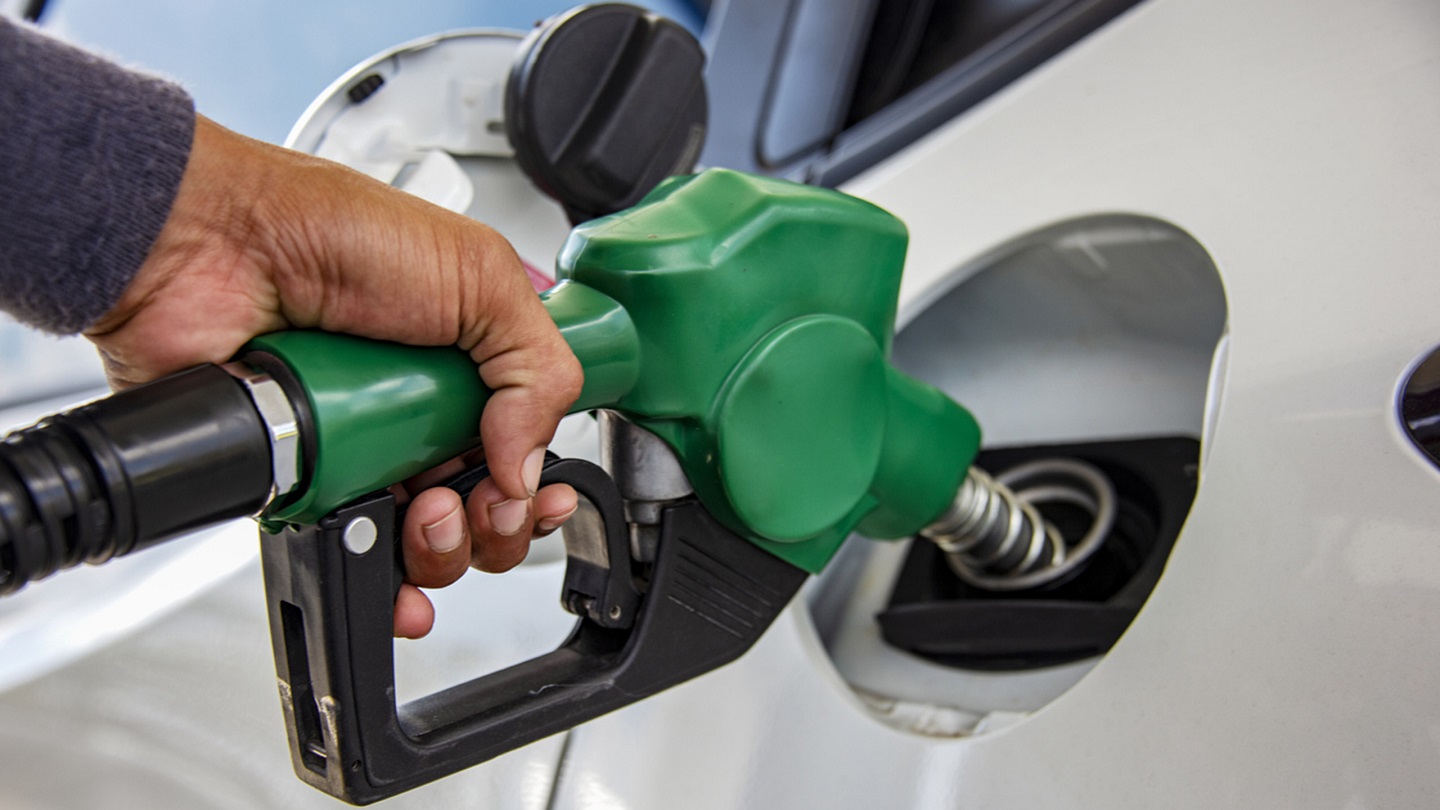 Man Handle pumping gasoline fuel nozzle to refuel. Vehicle fueling facility at petrol station. White car at gas station being filled with fuel. Transportation and ownership concept.