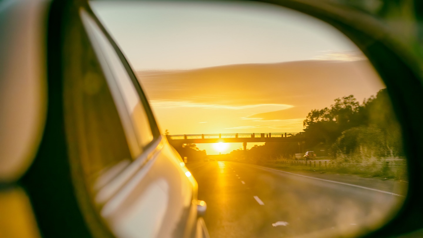 Road at sunset as seen from the car side mirror.