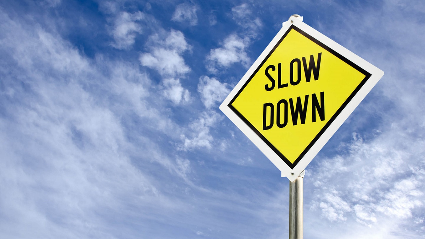 Slow Down yellow road sign on blue sky with clouds background