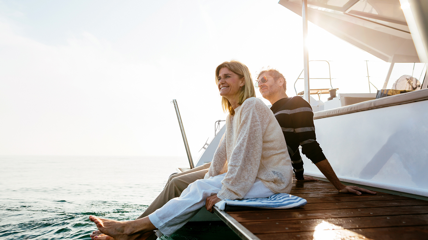 Mature couple sitting on jetty, relaxing at the sea